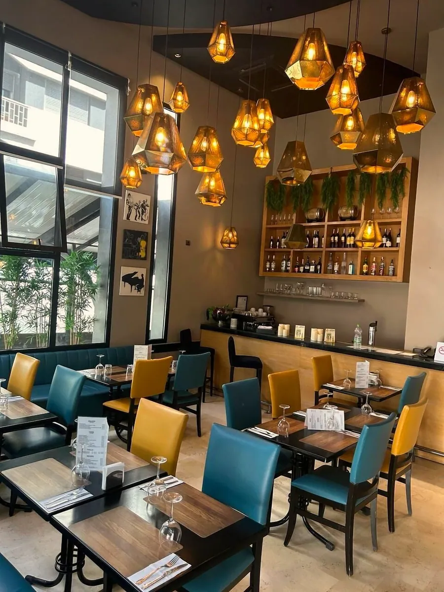Le bar et ses étagères, chaises bleu canard et moutarde