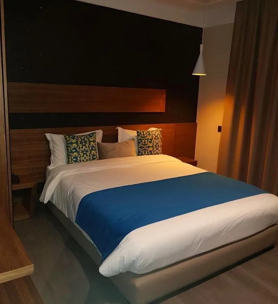 Chambre Deluxe, jeté de lit bleu, mur anthracite et tête de lit en bois sombre
