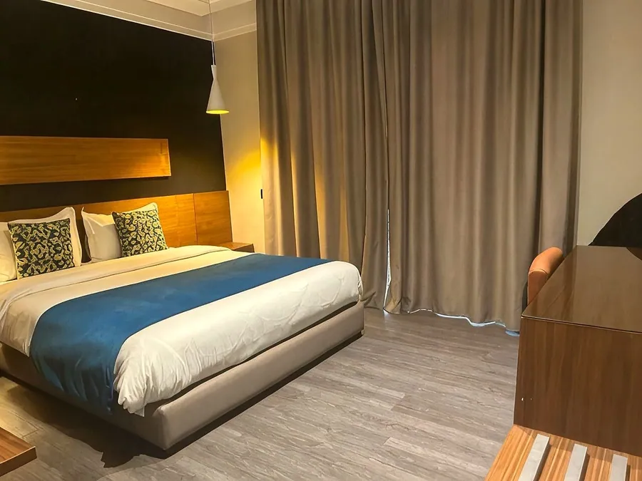 Chambre Deluxe, jeté de lit bleu, lampes allumées et grands rideaux